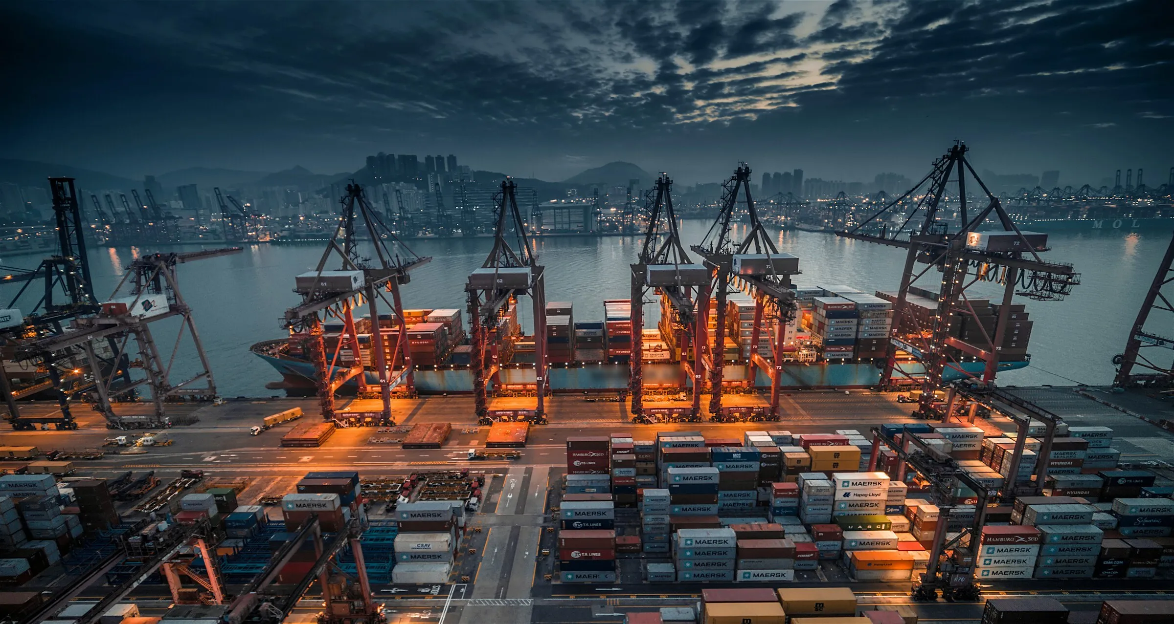 Container ship being loaded at a port in Hong Kong at dusk